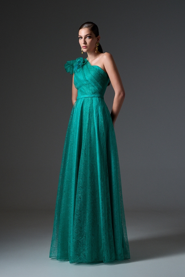 Evening long one-shoulder dress made of shiny lace with a flower on the shoulder
