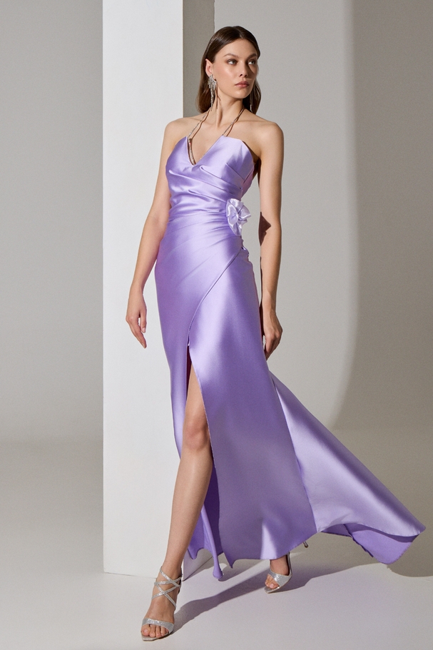 Evening long backless satin dress with a slit, chain at the neck, and flower on the side