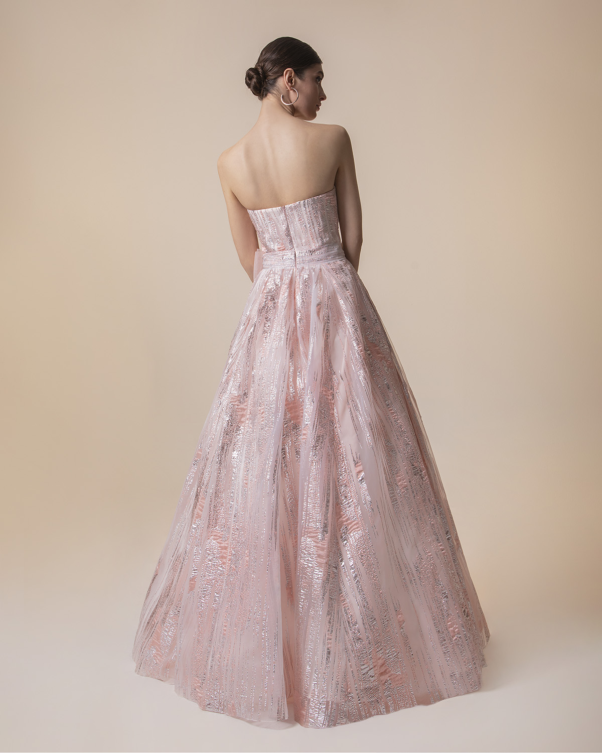 Long strapless evening dress with shining fabric and a big bow on the waist